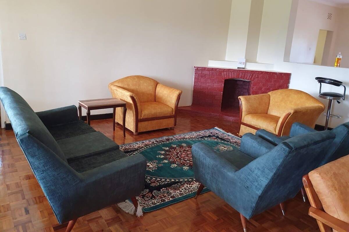 Una sala de estar con chimenea, dos sillones, un sofá y una mesita.