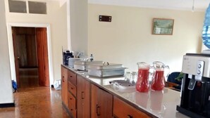Cucina con mobili in legno, piano di lavoro in acciaio inox e macchina da caffè.