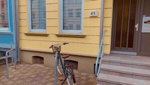 A bicycle parked outside a building with a number 41 sign, steps leading to a door, and a metal fence to the left. - Vacation apartment Hansetraum Lübeck (Lübeck)