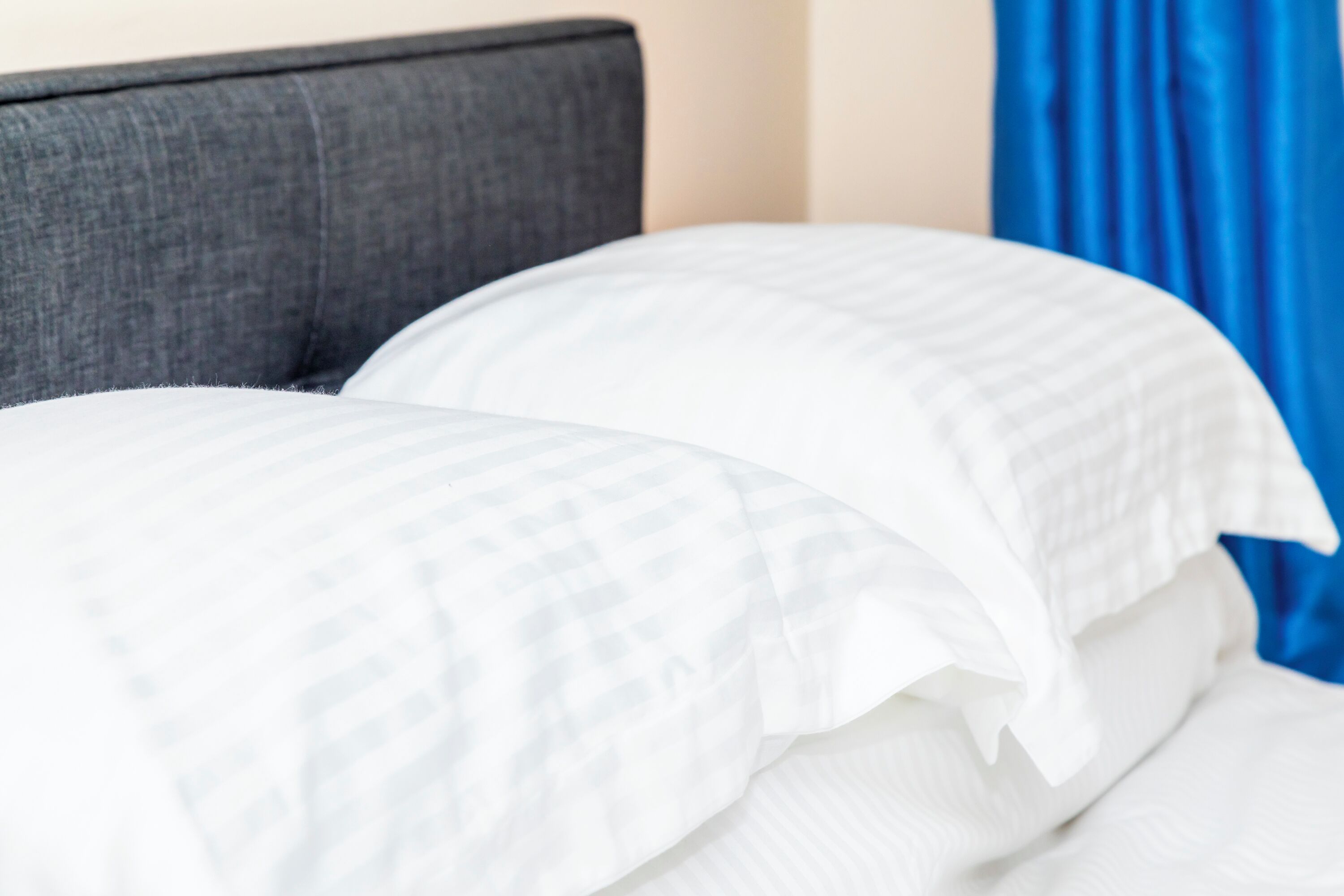 A bed with white bedding and a grey headboard.