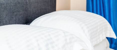 A bed with white bedding and a grey headboard.