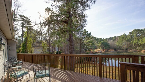 Une terrasse en bois avec des fauteuils à bascule et une vue sur un lac entouré d’arbres.