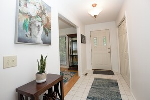 A hallway with a potted plant, a framed artwork, a door, and a patterned rug. - Rocken Lake Hills Retreat- Pinehurst Home w/ Game Room & Patio Near Golf (Pinehurst)