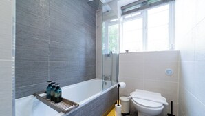 Un baño moderno con bañera, inodoro y zona de ducha.