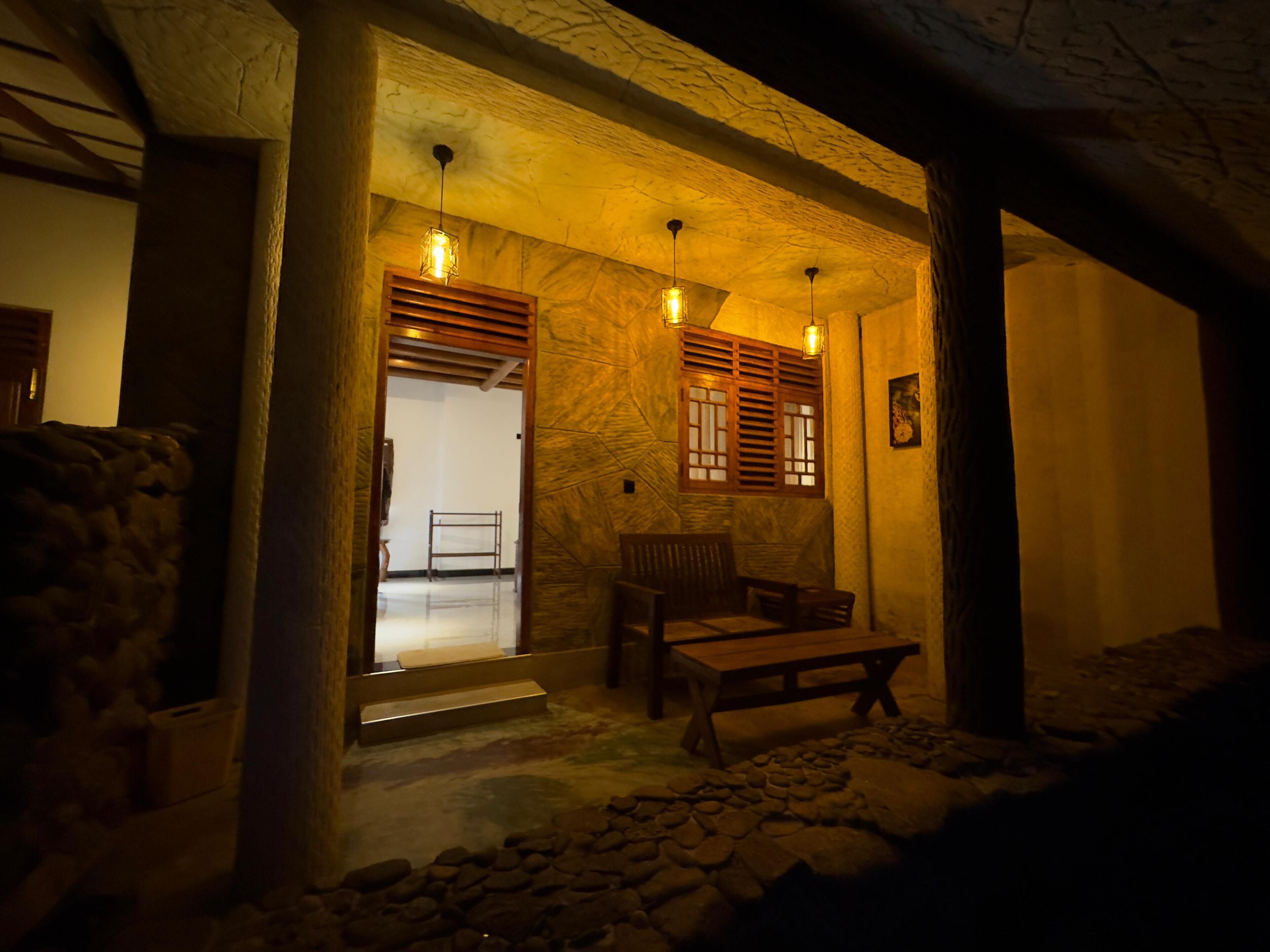 A dimly lit interior with a stone bench, wooden furniture, and a stone floor.