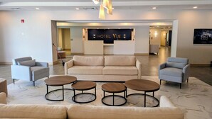 A hotel lobby with a reception desk, sofas, and round tables. - The Hotel Vue (Natchez)