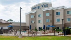 A hotel with a pool area, outdoor seating, and a fenced courtyard. - The Hotel Vue (Natchez)