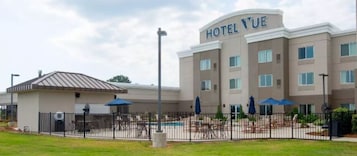 A hotel with a pool area, outdoor seating, and a fenced courtyard.