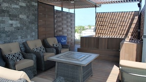 Un espace extérieur aménagé en terrasse, avec des meubles en osier, une table carrée et une plateforme en bois.