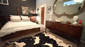 A bedroom with a large bed, a dresser, a mirror, and a cowhide rug. - Artist Loft in the Heart of Chelsea with BBQ & terrace, Pet friendly! (New York)