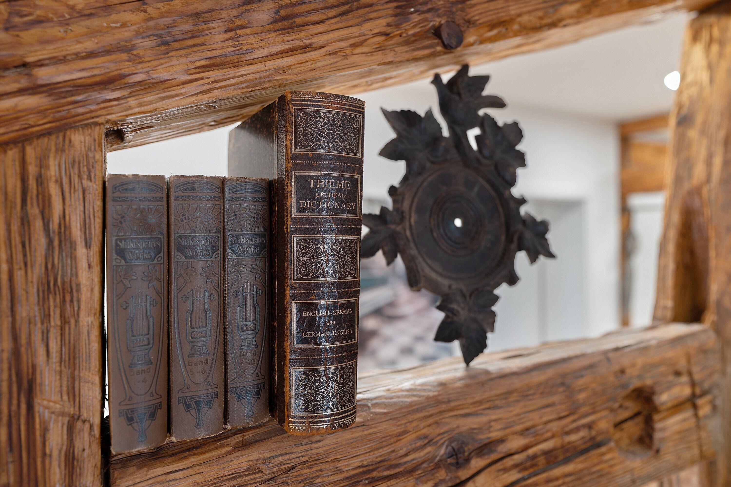 Uma estante de madeira com livros e uma peça decorativa de madeira.