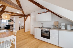 A modern kitchen with white cabinetry, a built-in oven, and a coffee maker.