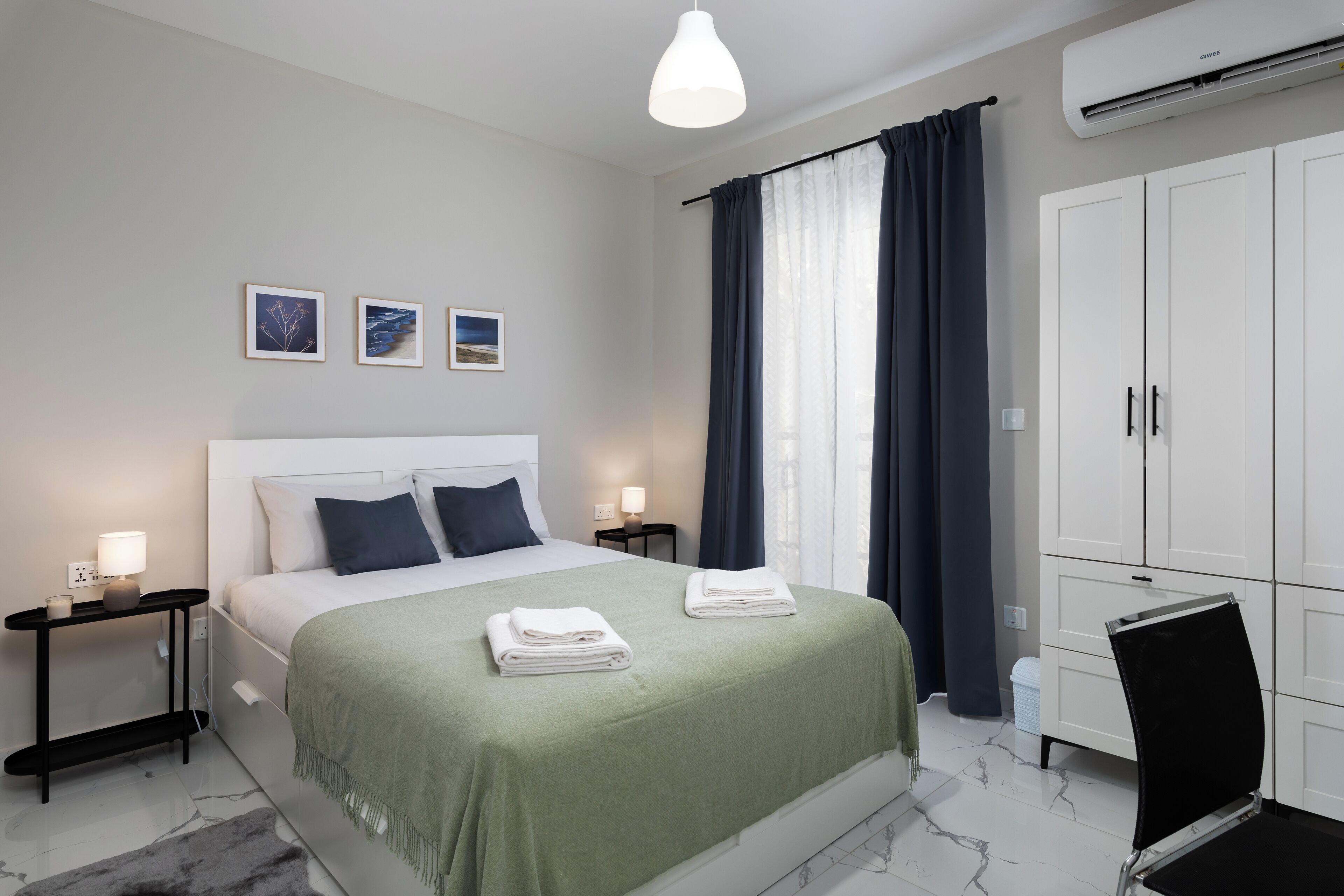 A modern bedroom with a neatly made bed, a desk, and a wardrobe.