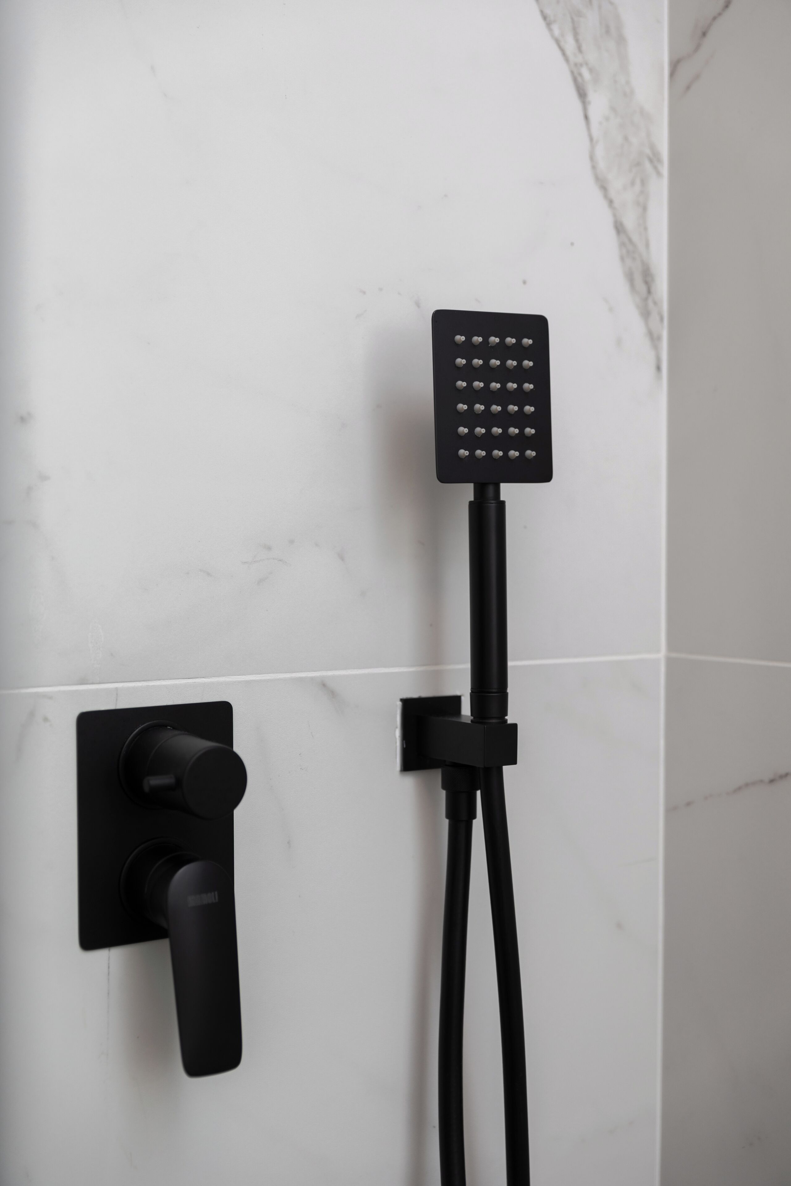 Um banheiro moderno com controle de chuveiro embutido na parede e chuveiro manual.