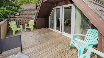 A wooden deck with outdoor seating and a sliding glass door leading to an interior space.