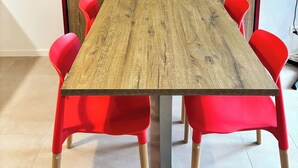 A conference table with four red chairs and a wooden partition in a room with tiled flooring.