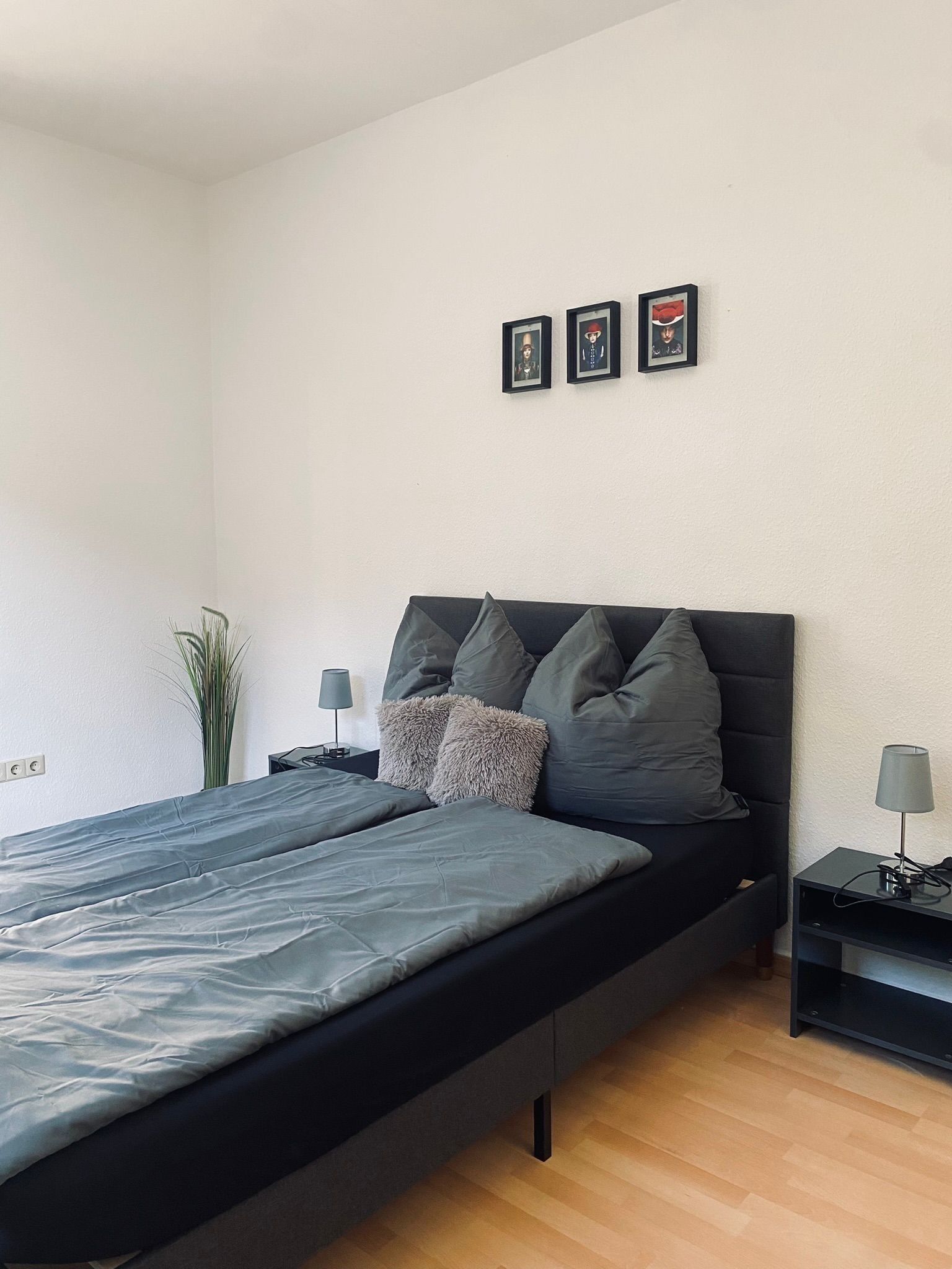 Un dormitorio moderno con una cama individual, una mesita de noche, una lámpara y tres cuadros en la pared.
