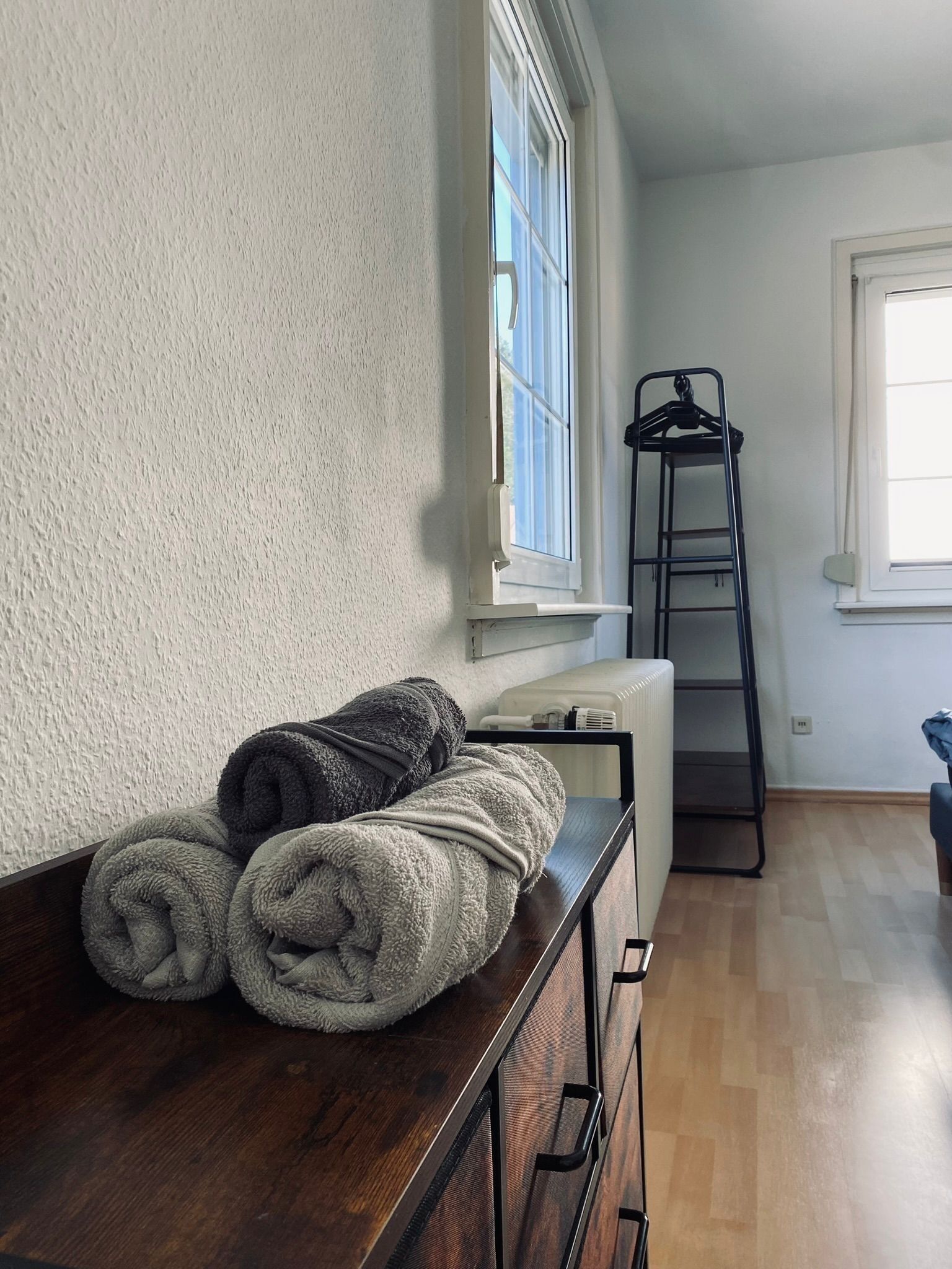 A room with a wooden dresser, a radiator, and a window with a view.