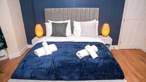 Un lit bien fait, avec une couverture bleue, deux oreillers et deux serviettes enroulées.