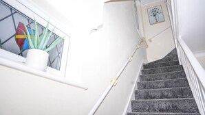 Un escalier avec une rampe blanche et un pot de fleurs placé sur le palier.