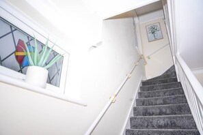 A staircase with a white handrail and a potted plant on the landing. - Spacious 4-Bed Contractor Home | Heathrow & M4 | Free Parking (Hounslow)
