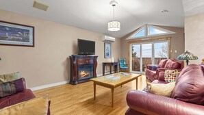 Una sala de estar con chimenea, sofás de cuero, una mesa de centro de madera y un televisor.