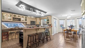 Una cocina moderna con barra, espacio para almacenamiento de vino empotrado y una mesa de comedor amplia.