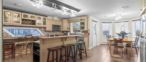 A modern kitchen with a bar area, built-in wine storage, and a large dining table.