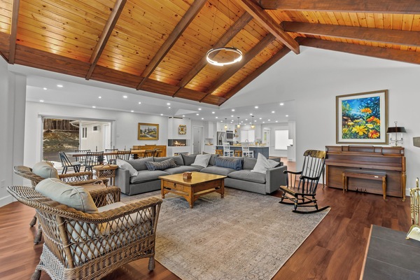 Stunning great room featuring soaring vaulted wood ceilings, a large sectional for gathering, and a cozy fireplace.