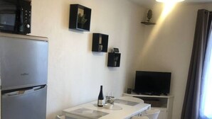 Ett kompakt bostadsutrymme med ett litet kök, en matplats och en tv.
