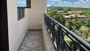 Un balcone con pavimento decorato e ringhiera in metallo, affacciato su un paesaggio con case e vegetazione.