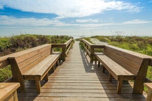 A wooden boardwalk with benches leading to a body of water, surrounded by vegetation. - St. Augustine Beach 323: Pool, Views & Comfort 2 Bedroom Condo (St. Augustine)