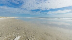 Une vaste plage de sable fin, avec des vagues douces et un ciel dégagé.