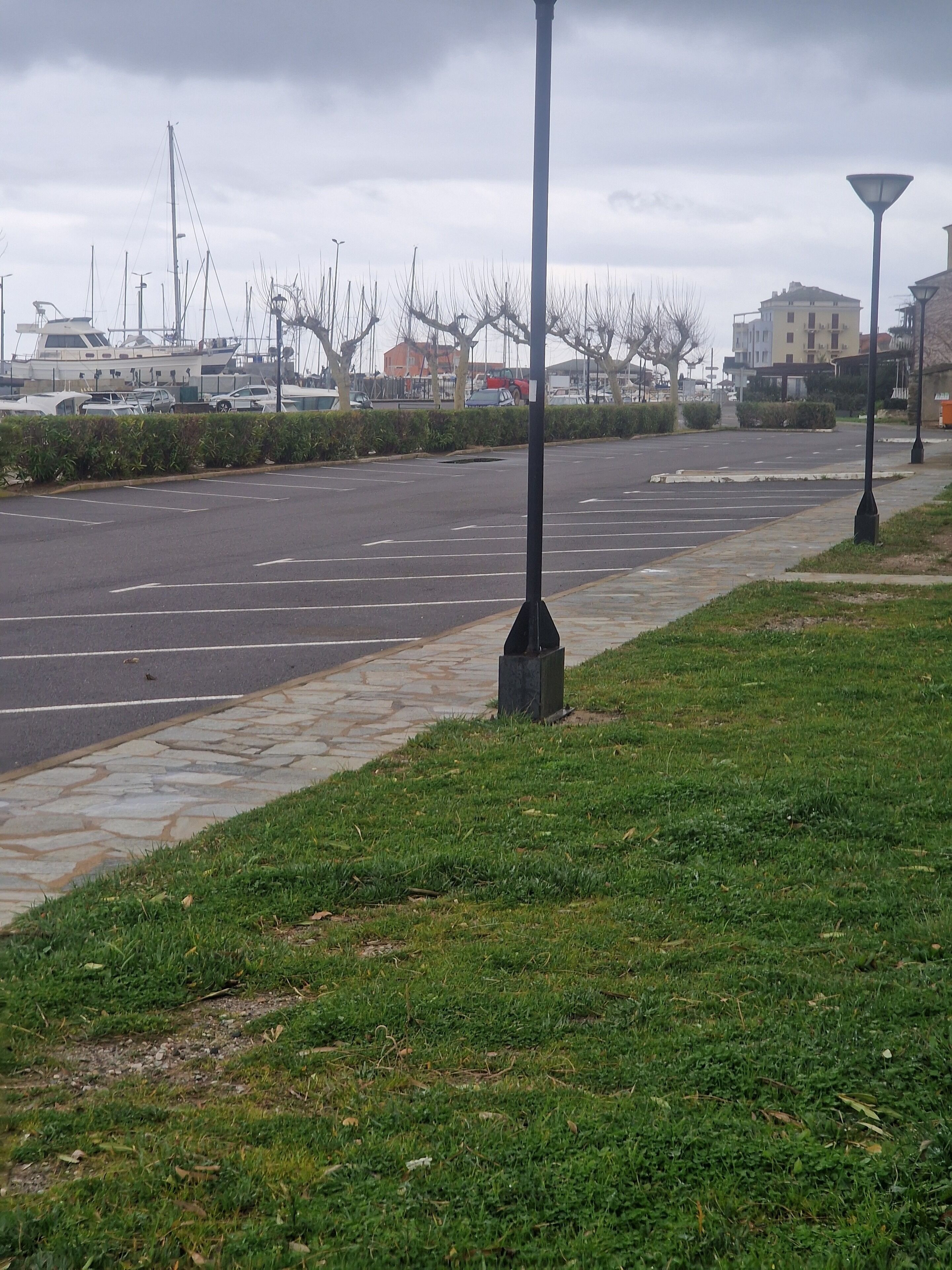 Un estacionamiento con césped y farolas.