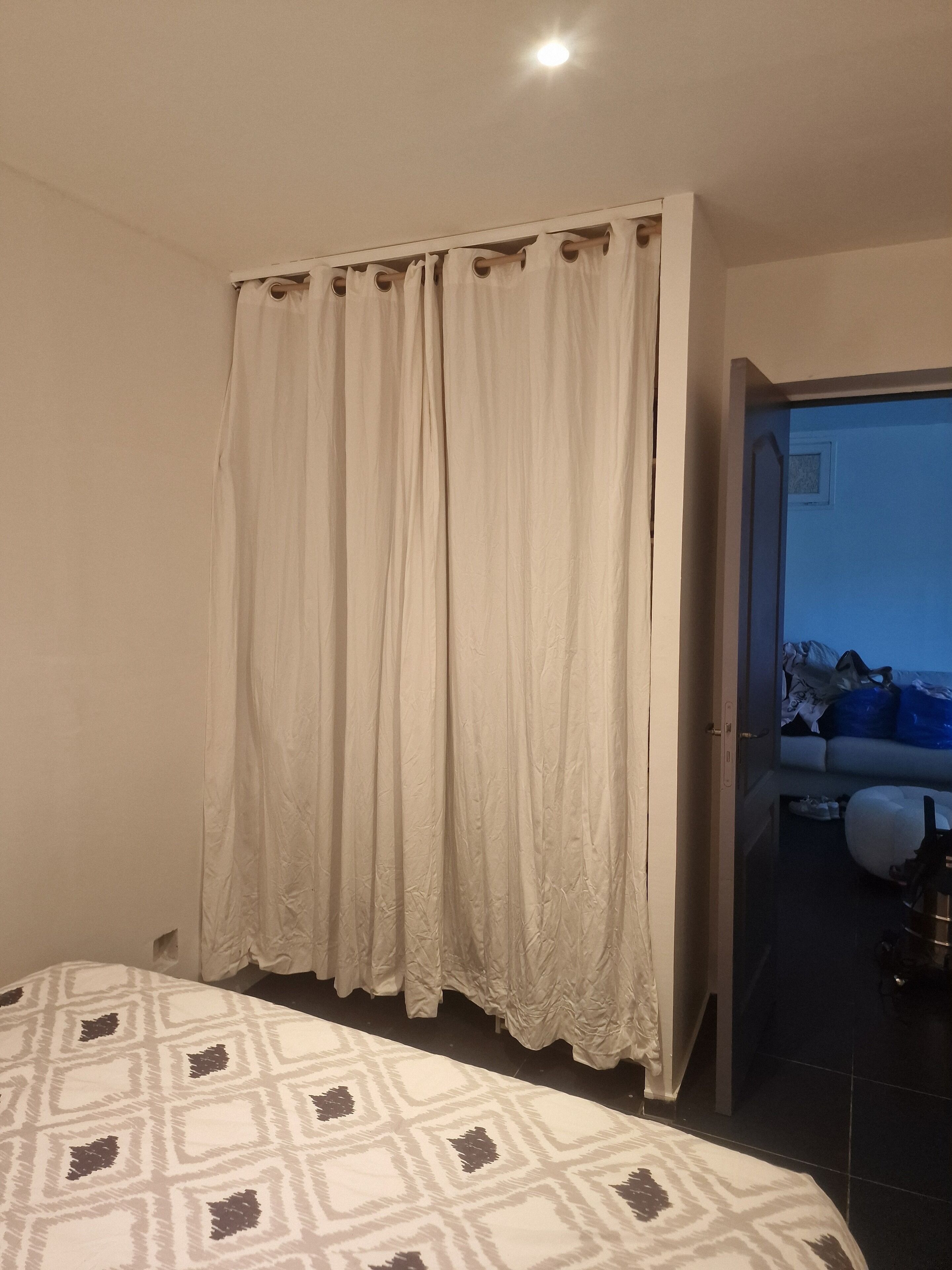 A bedroom with a bed, a curtain, and a view of a bathroom.
