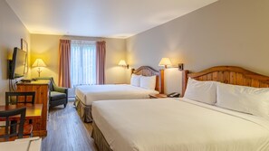 A hotel room with two beds, a desk with a chair, a television, and lamps.