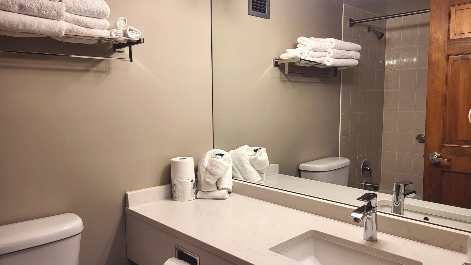 A bathroom with a sink, mirror, toilet, and towel rack.