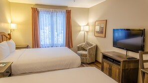 Una habitación de hotel con dos camas, televisión, una silla y un escritorio.
