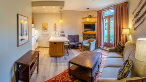 A compact living space with a kitchenette, a dining area, a sofa, and a TV.