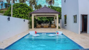 A swimming pool with lounge chairs and a covered seating area.