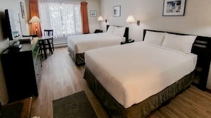 A hotel room with two beds, a desk, a chair, and a window with curtains.