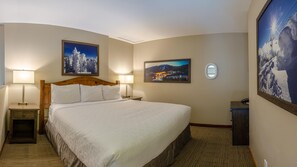 A hotel room with a large bed, two bedside tables with lamps, a nightstand, and two framed pictures on the walls. - Cahilty #432 Hotel Room (Sun Peaks)