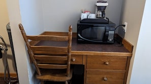 A wooden chair with a drawer unit beside it, a microwave, and a coffee maker on a countertop. - Cahilty #333 Hotel Room (Sun Peaks)