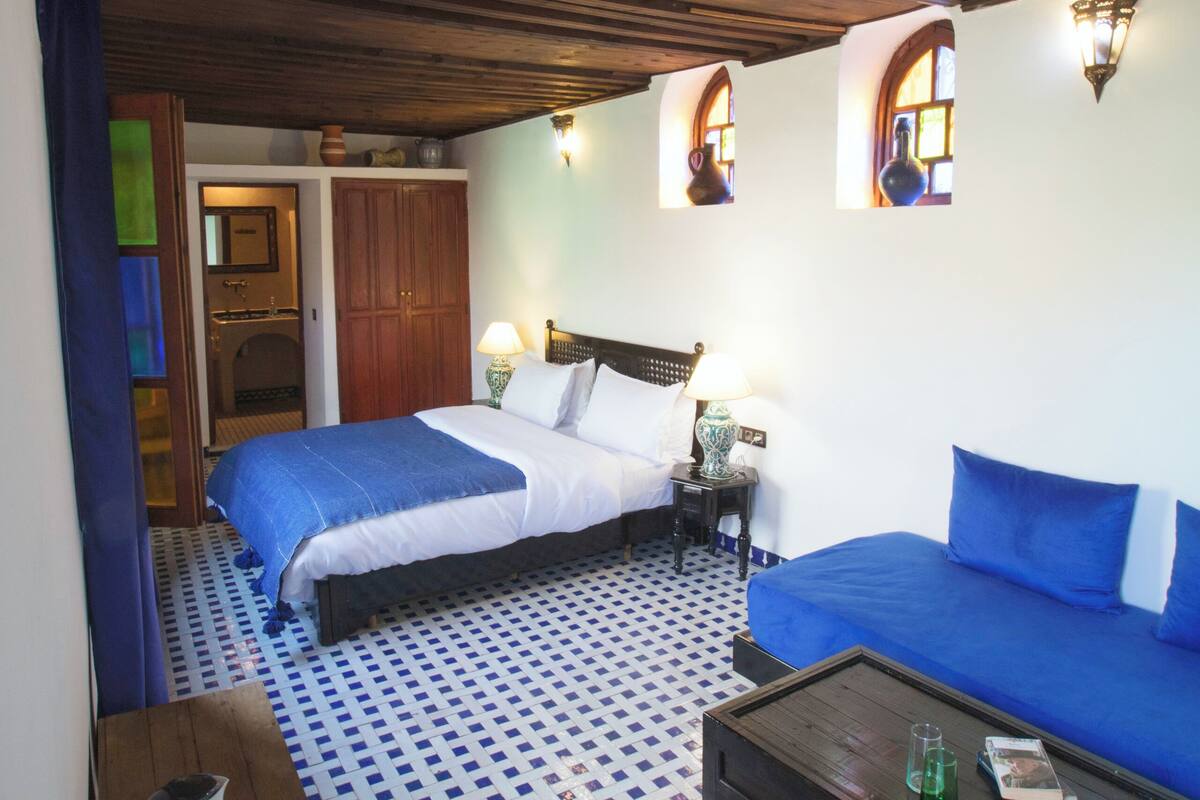 Una habitación con dos camas, un sofá, una mesa de centro y piso estampado.