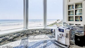 A bathroom with a large window overlooking a beach, a marble floor, and a coffee machine. - Ocean Paradise 4 Bedroom Home (St. Augustine)