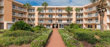 Un hotel de varios pisos con un patio central, balcones y abundante vegetación.