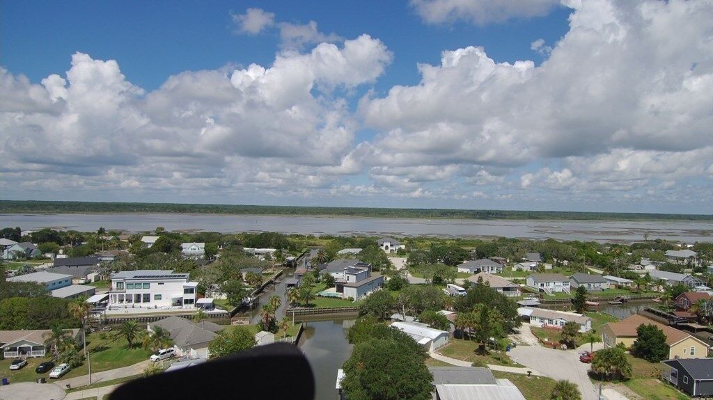 A residential area with houses, a river, and a clear sky.