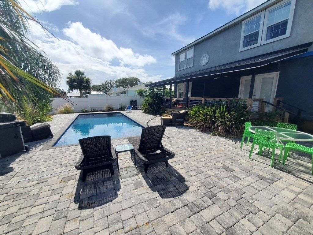 Un jardin avec une piscine, deux chaises longues et une table.