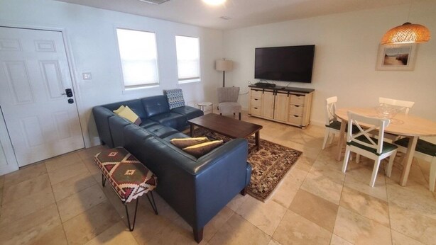 A living room with a sofa, coffee table, TV, and dining area. - Zen Cottage - All 4 Bedroom Home (St. Augustine)