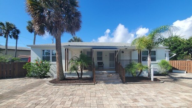 A single-story house with a front porch, a driveway, and a palm tree. - Charming Beach Studio With Wifi & Beach Access 1 Bedroom Home (St. Augustine)